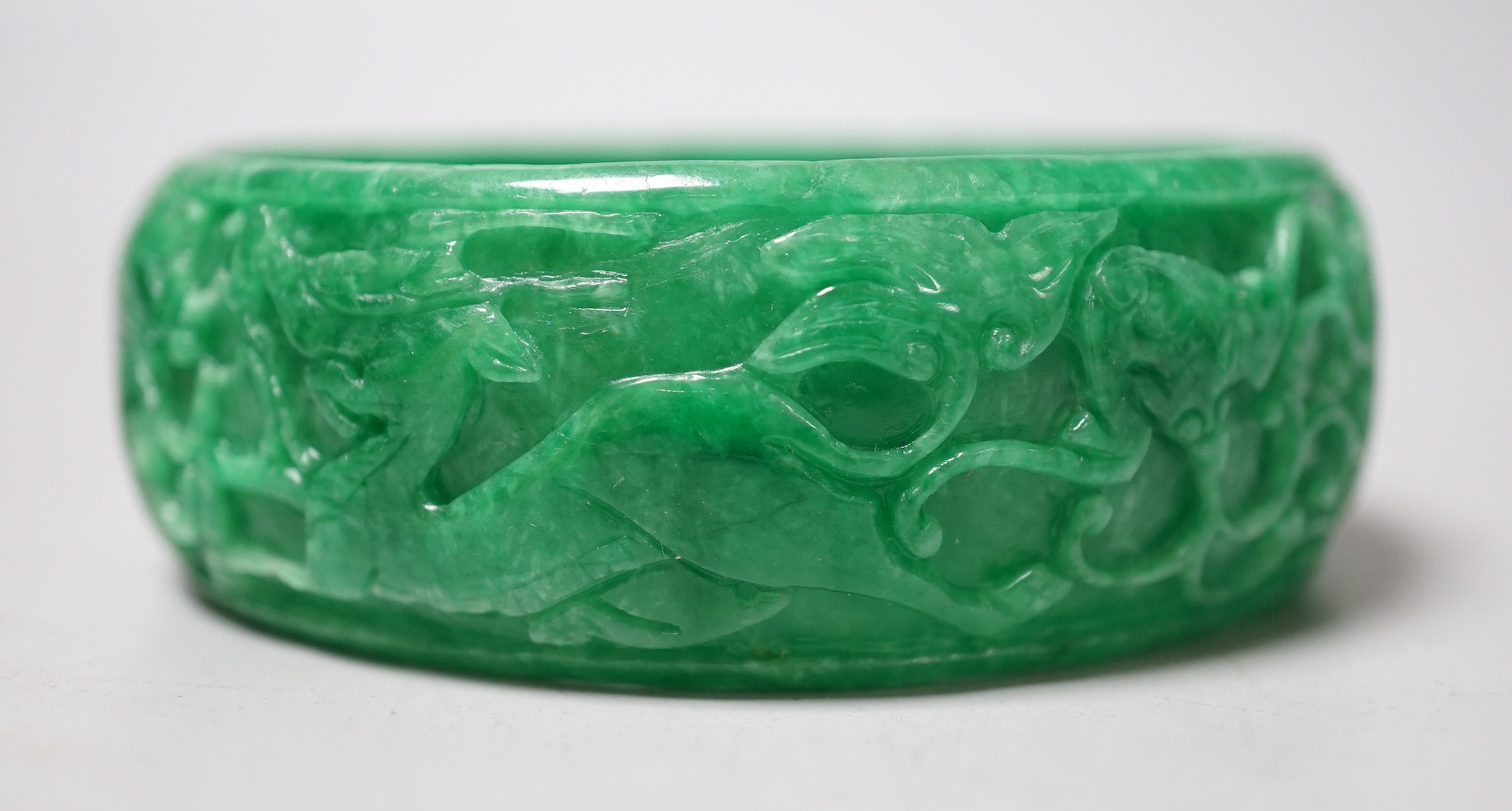 A Chinese carved jadeite bangle, 8.5cm diameter
